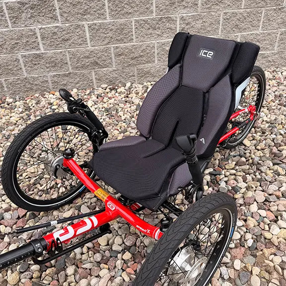 Closeup view of the seat and quick adjust on the ICE Demo Sprint Pixel RS STEPS EP6 Passion Red Recumbent Trike in an outdoor setting.