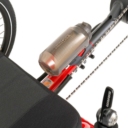 Angled view of the Fidlock TWIST 750 Compact Single Bottle in Smoke mounted on a red recumbent trike against a white background.