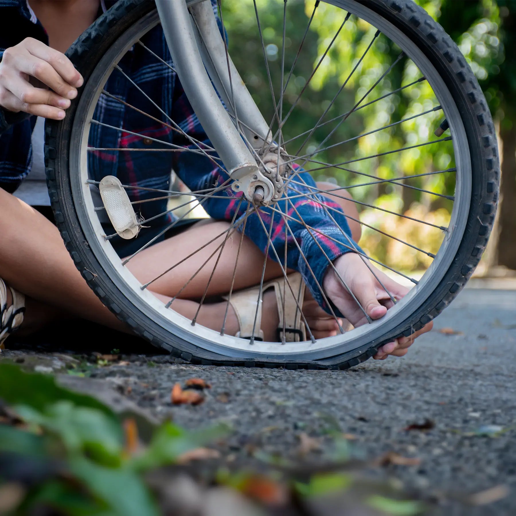 A person examines a flat tire on their bicycle.
