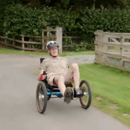 The GRIDE Solutions GXT Plus E-Trike Drive System for 20 inch Rear Wheels mounted on a blue ICE trike, which a man rides down the road.