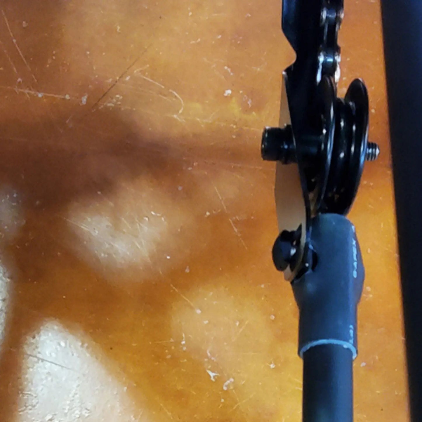 View of the black Hase Chain Tube Plastic Bracket Half Tube installed on a Hase Trike against an orange concrete background.