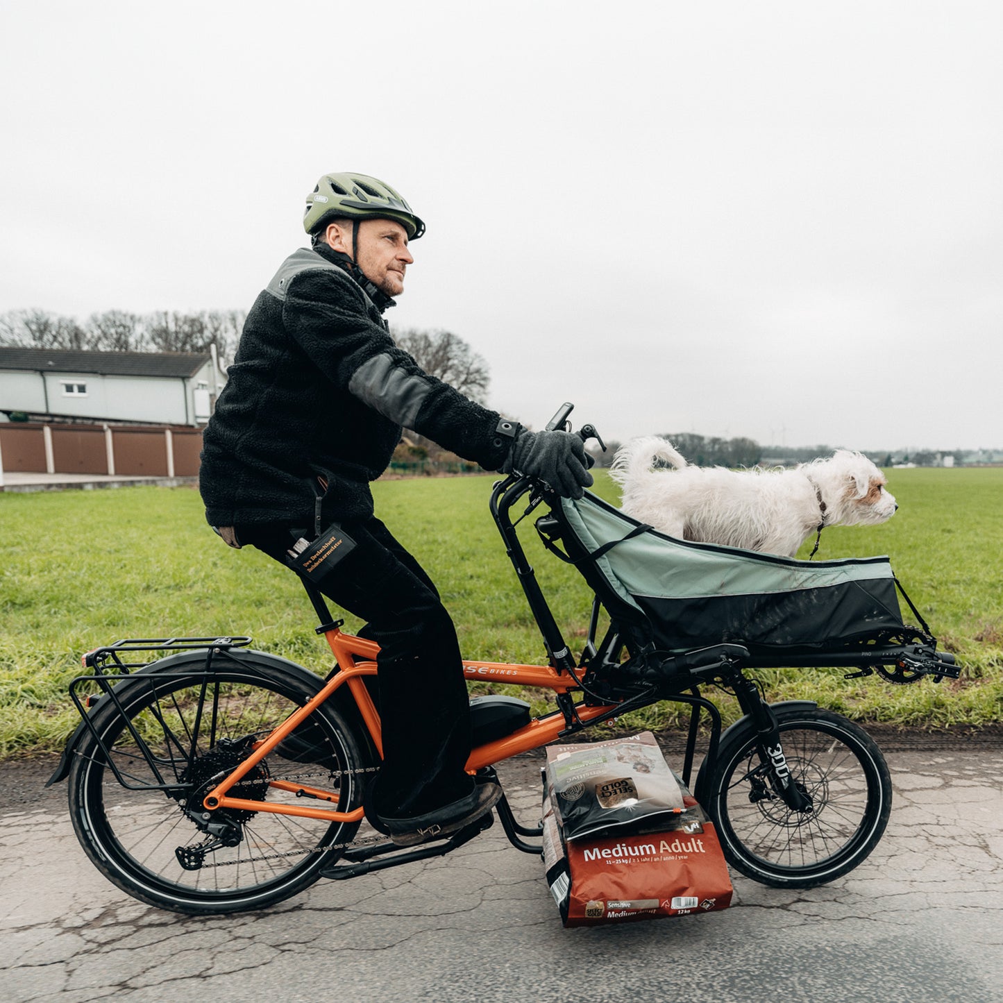A man and his ride the Hase Pino EP6 Cargo Grey Beige Tandem Recumbent Bike in a country setting.