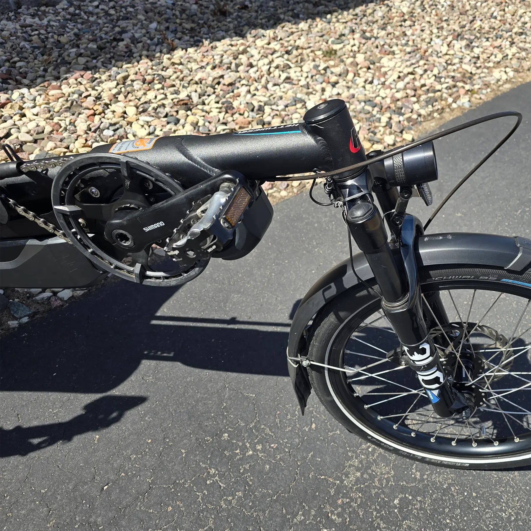Closeup view of the crank, fork, headlight  and front wheel on the Hase Used 2022 Kettwiesel Evo Steps 6100 with 630wh Battery and 2A Charger Recumbent Trike in an outdoor setting.