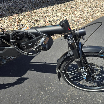 Closeup view of the crank, fork, headlight  and front wheel on the Hase Used 2022 Kettwiesel Evo Steps 6100 with 630wh Battery and 2A Charger Recumbent Trike in an outdoor setting.