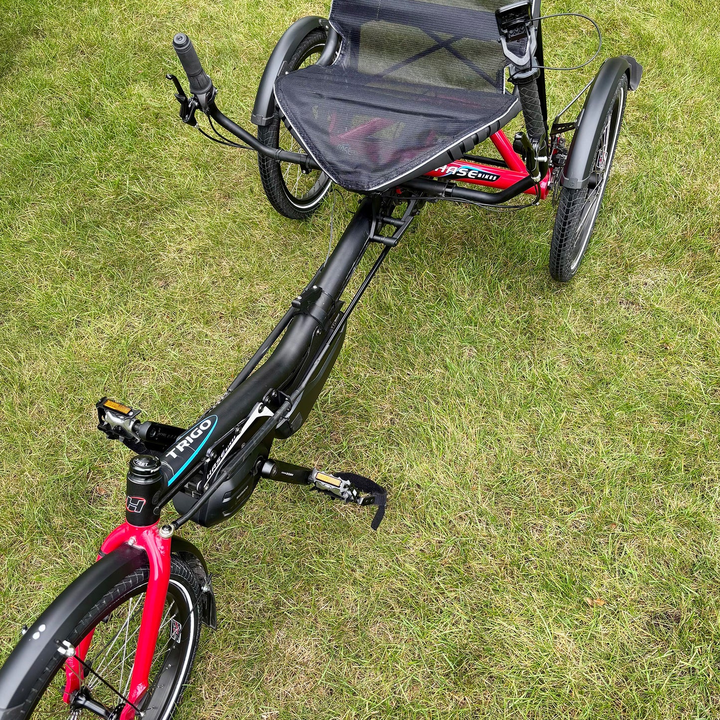Close-up of three-wheeled Hase Trigo recumbent trike on grass.