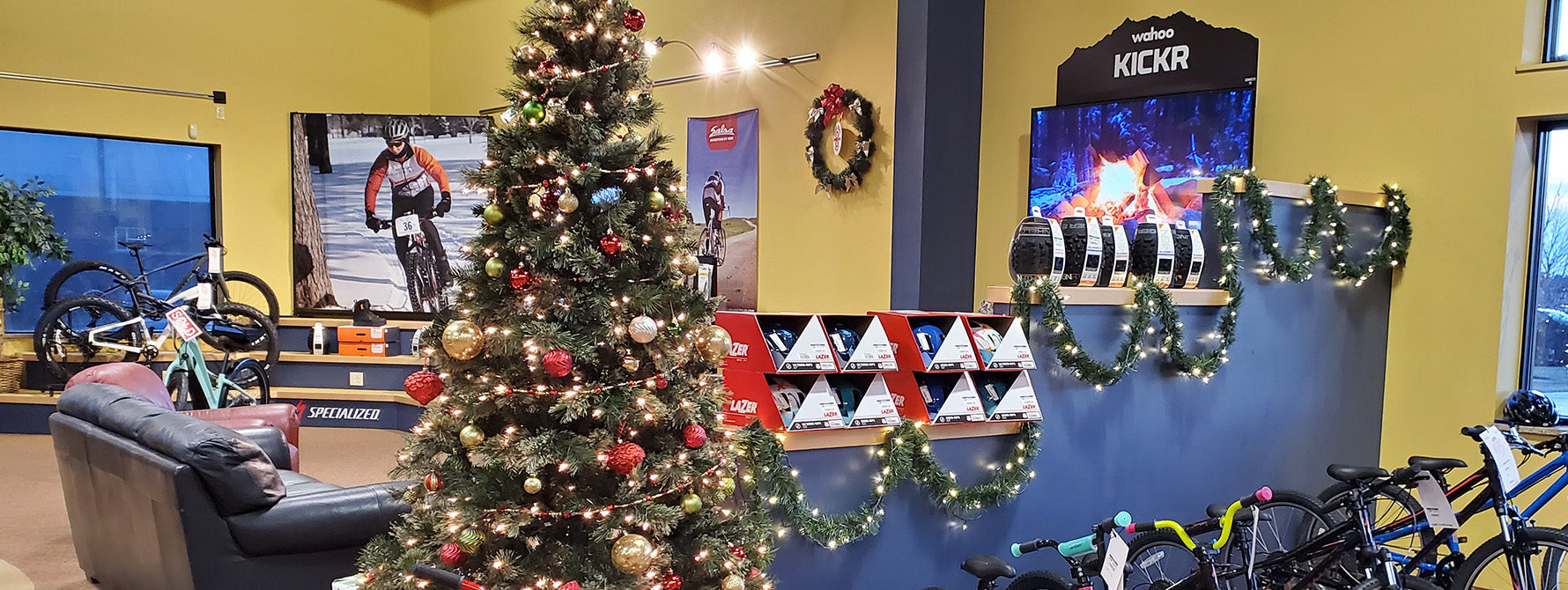 Bicycle store interior with a Christmas tree, bicycles, and promotional posters.