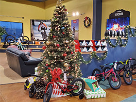 Bicycle store interior with a Christmas tree, bicycles, and promotional posters.