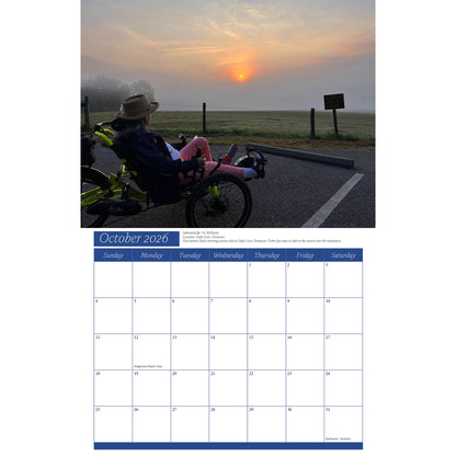 Calendar page for October 2026 with a photo of a person on a recumbent trike watching a sunset.