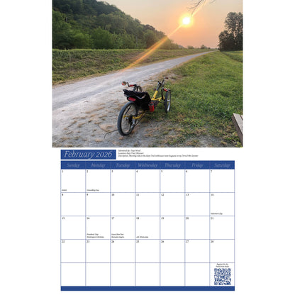 Calendar page for February 2026 with a scenic sunset recumbent trike photo and calendar layout.