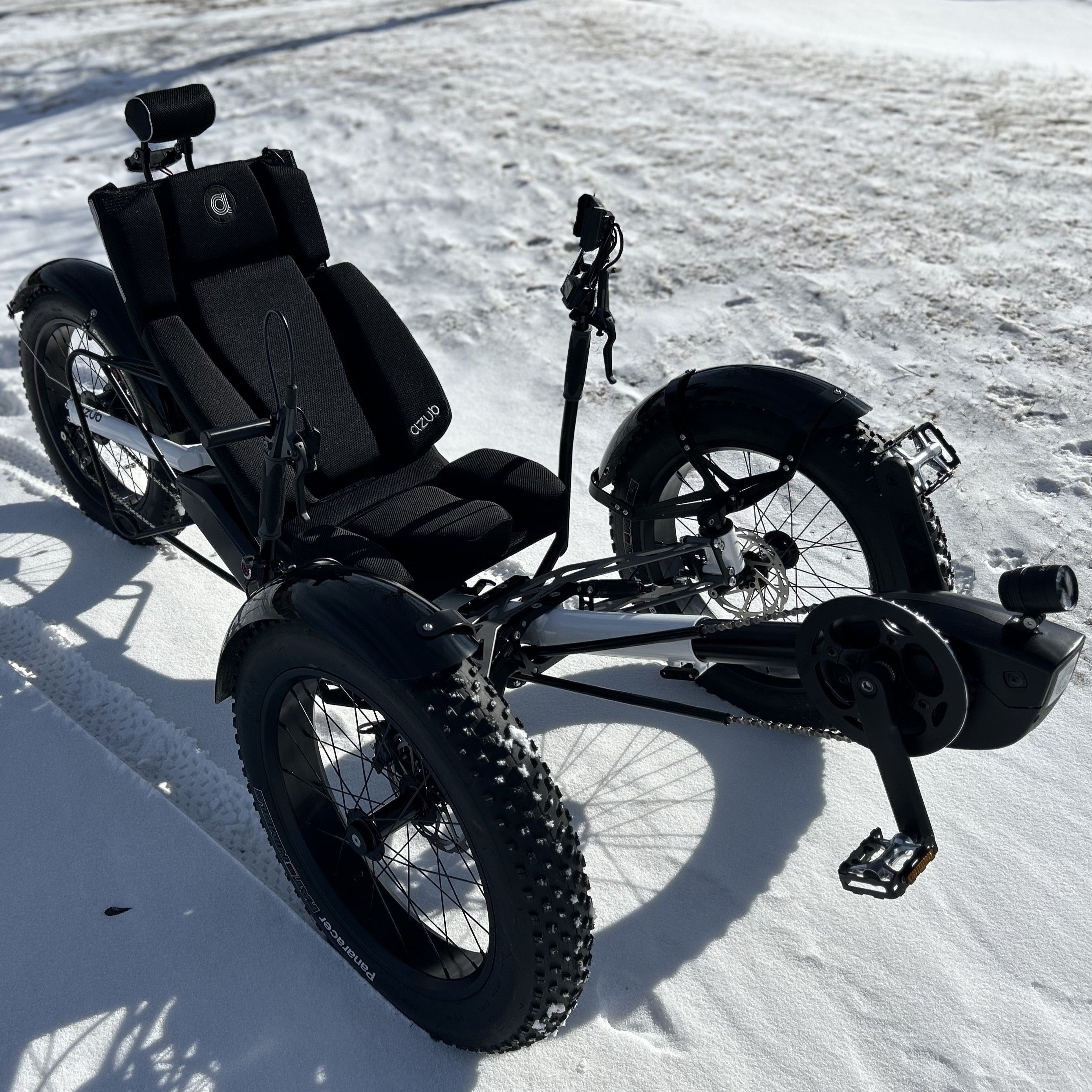 Angled side view of the Azub Limited Edition Ti-Fly X Bosch Performance CX with Rohloff E14 shiny white recumbent trike against a white snowy background.