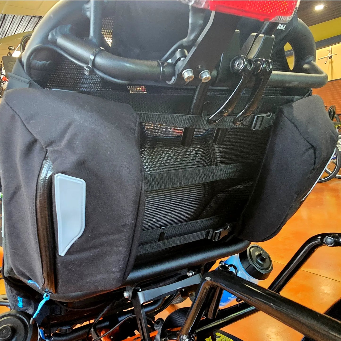View of the HP Velotechnik Add-On Bags for Mesh Seat in black with a reflective stripe mounted on a trike.