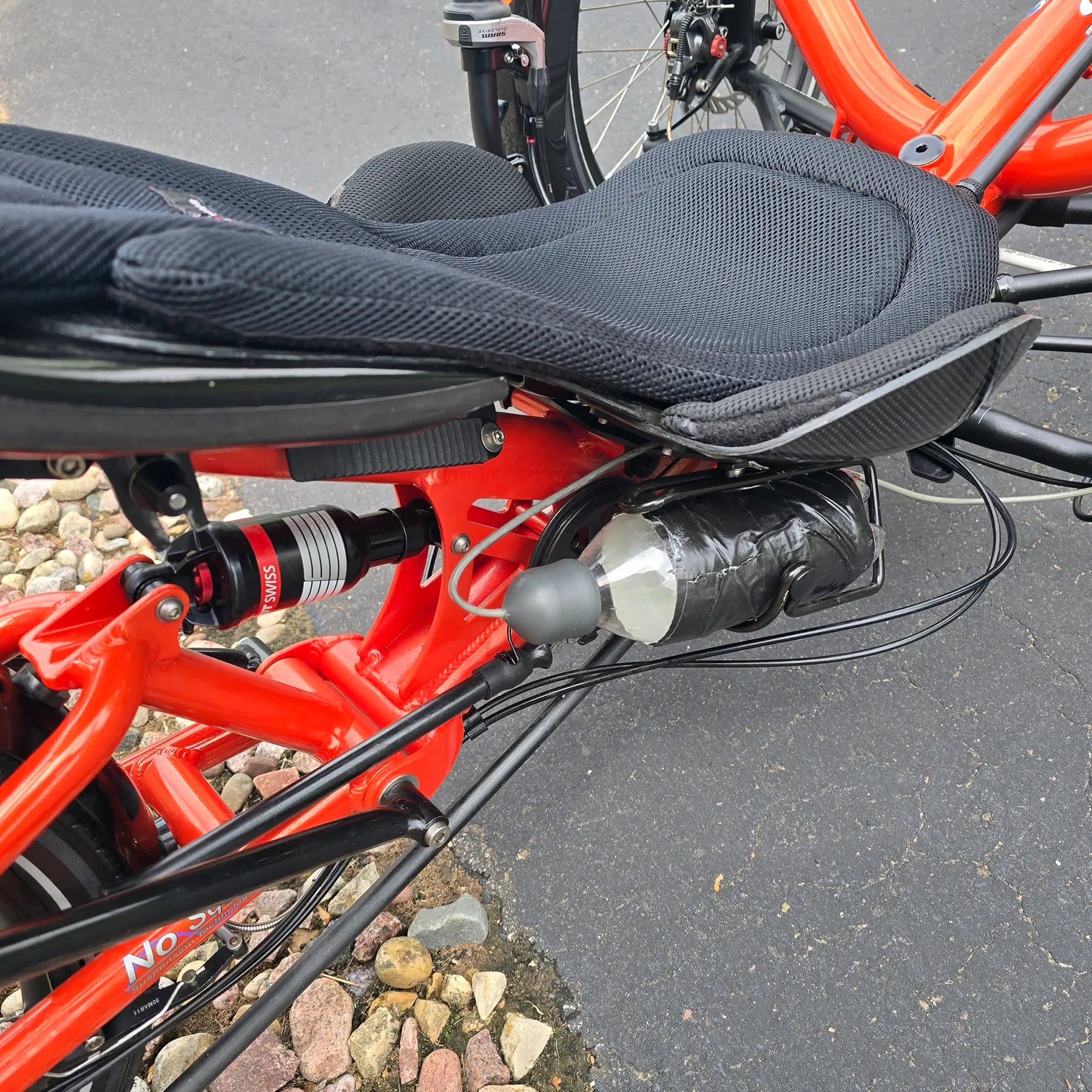 Closeup view of the rear shock, seat and horn on the HP Velotechnik Used Scorpion fs 20 Orange Recumbent Trike in an outdoor setting. 
