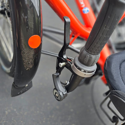 Closeup view of the front shifter and parking brake on the HP Velotechnik Used Scorpion fs 20 Orange Recumbent Trike in an outdoor setting. 