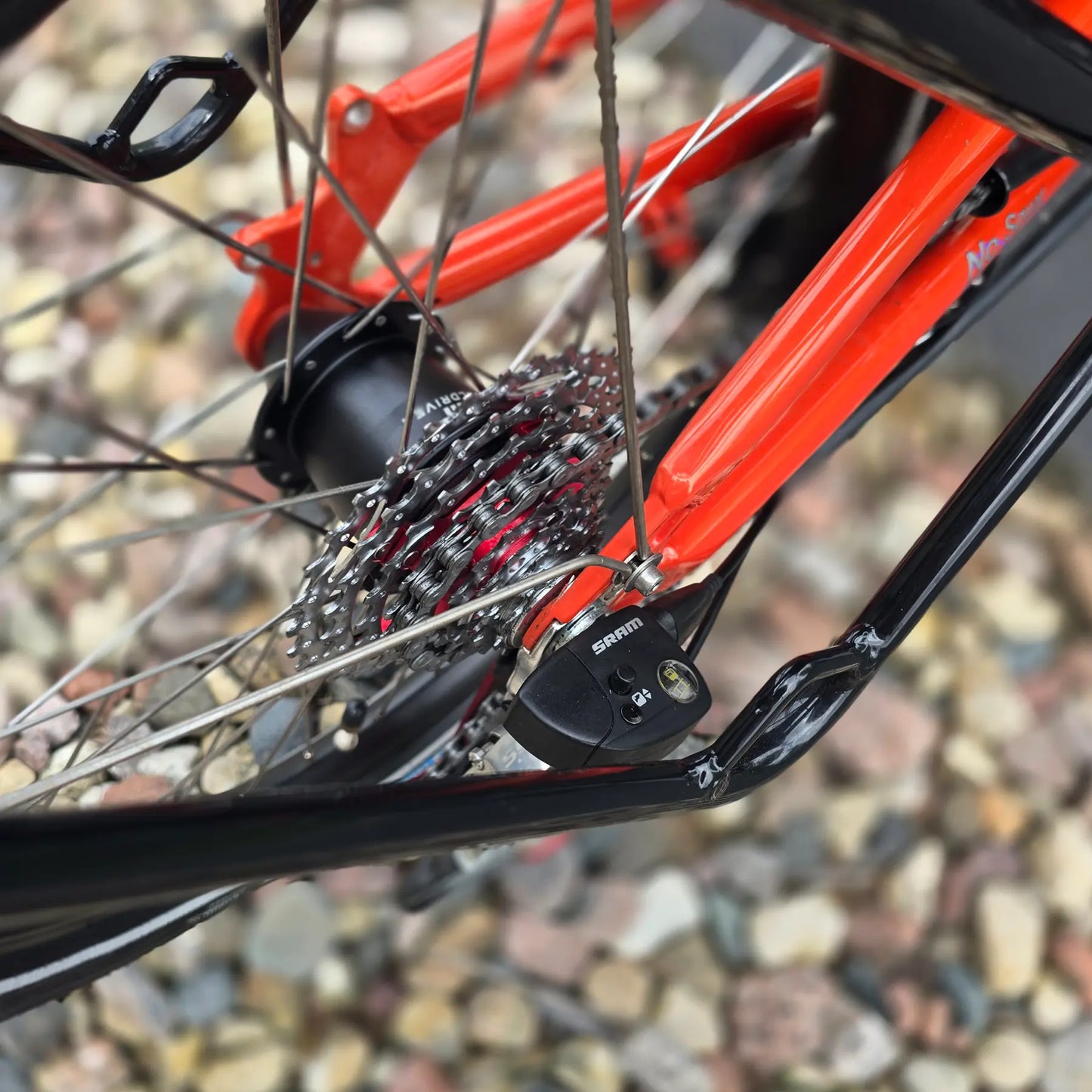 Closeup view of the rear cassette and SRAM Dual Drive on the HP Velotechnik Used Scorpion fs 20 Orange Recumbent Trike in an outdoor setting. 