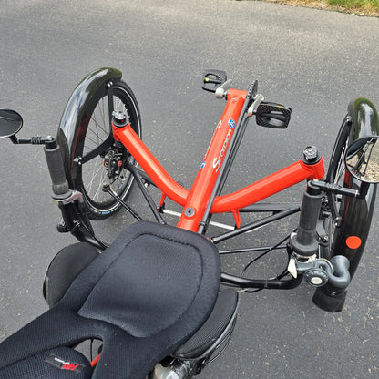Closeup view of the mirrors, controls and front fenders on the HP Velotechnik Used Scorpion fs 20 Orange Recumbent Trike in an outdoor setting. 