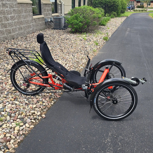 Drive side view of the HP Velotechnik Used Scorpion fs 20 Orange Recumbent Trike in an outdoor setting.
