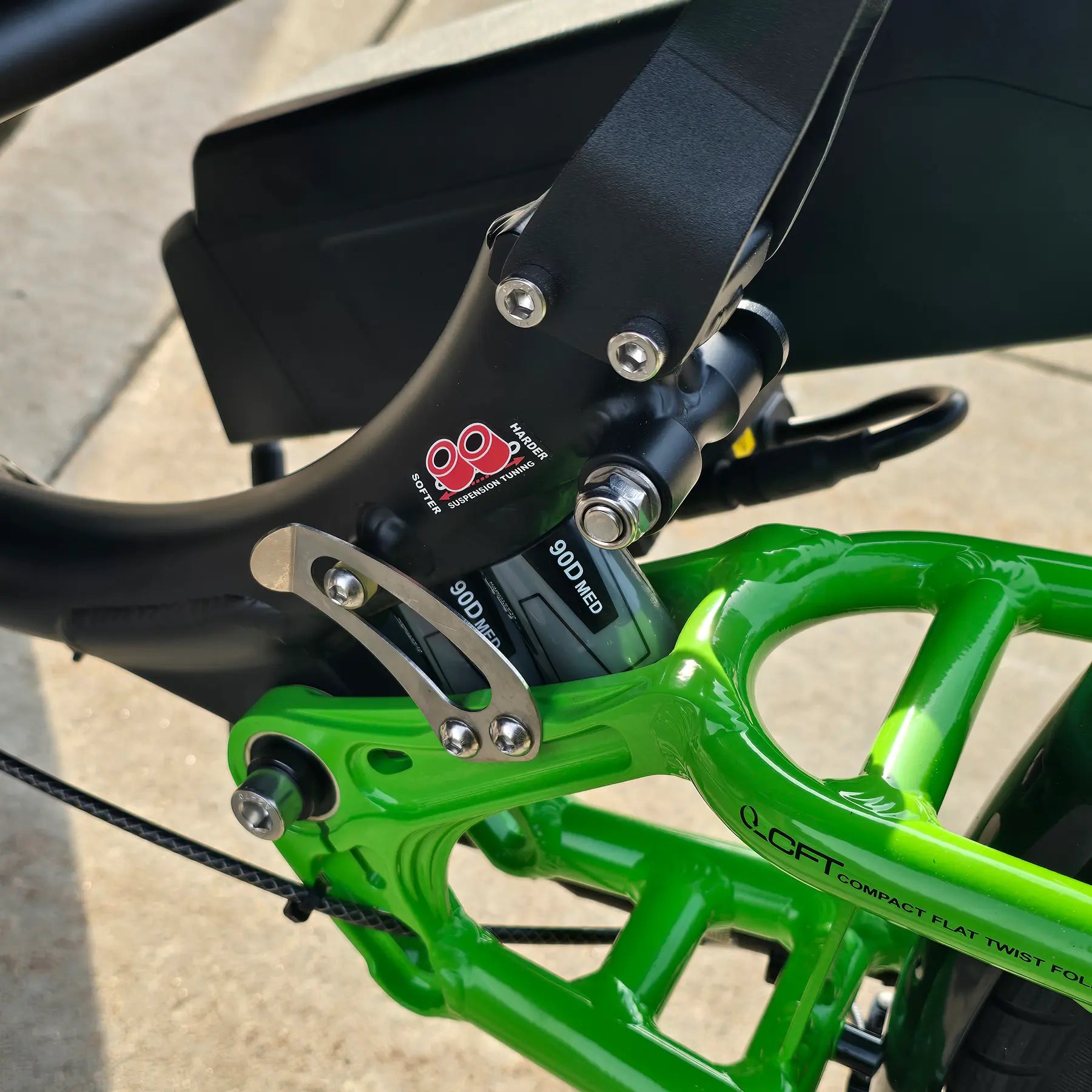 Closeup view of the rear suspension on the ICE Adventure HD 26 FS PERS Chainless Kiwi Green Recumbent Trike on a bike path.