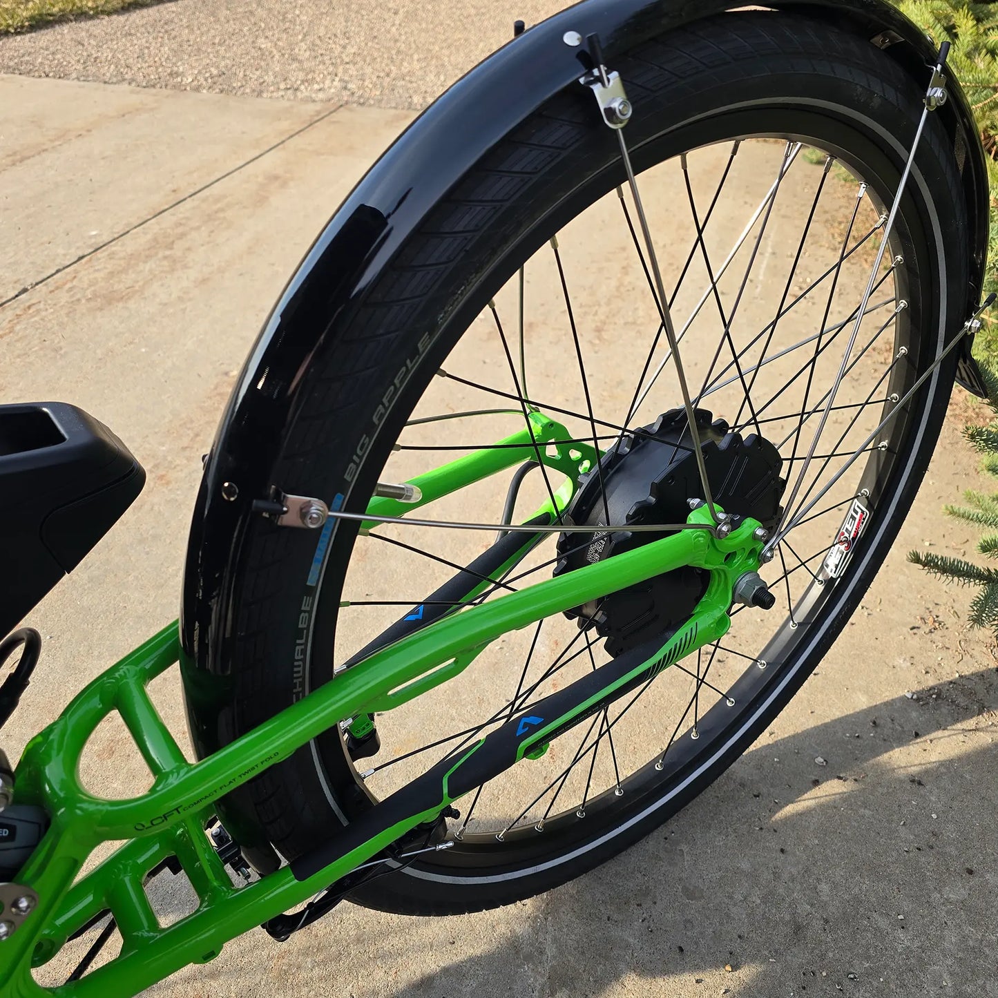 Closeup view of the rear wheel on the ICE Adventure HD 26 FS PERS Chainless Kiwi Green Recumbent Trike on a bike path.