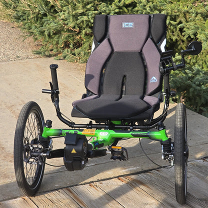 Front view of the ICE Adventure HD 26 FS PERS Chainless Kiwi Green Recumbent Trike on a bike path by a pine tree.