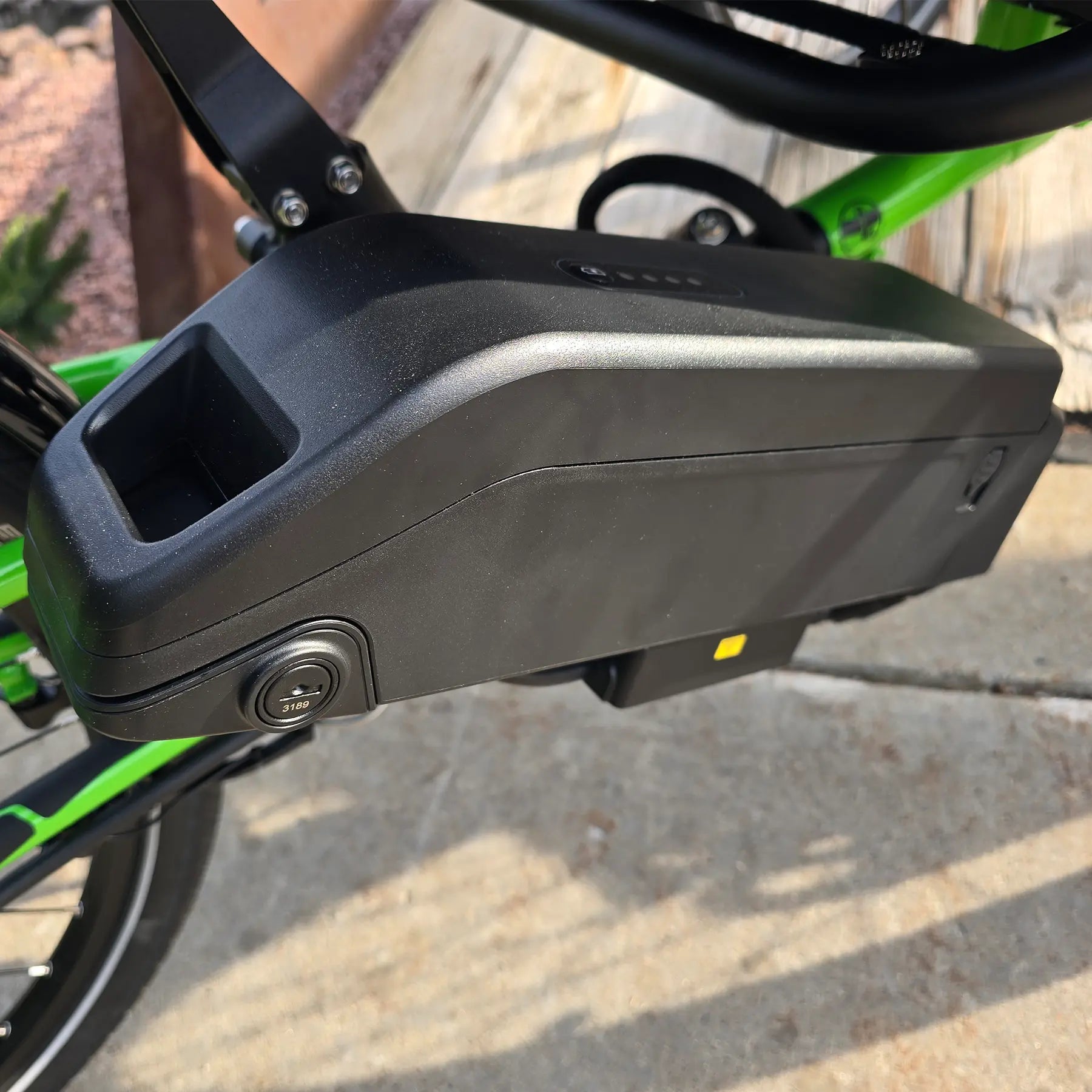 Closeup view of the battery on the ICE Adventure HD 26 FS PERS Chainless Kiwi Green Recumbent Trike on a bike path.