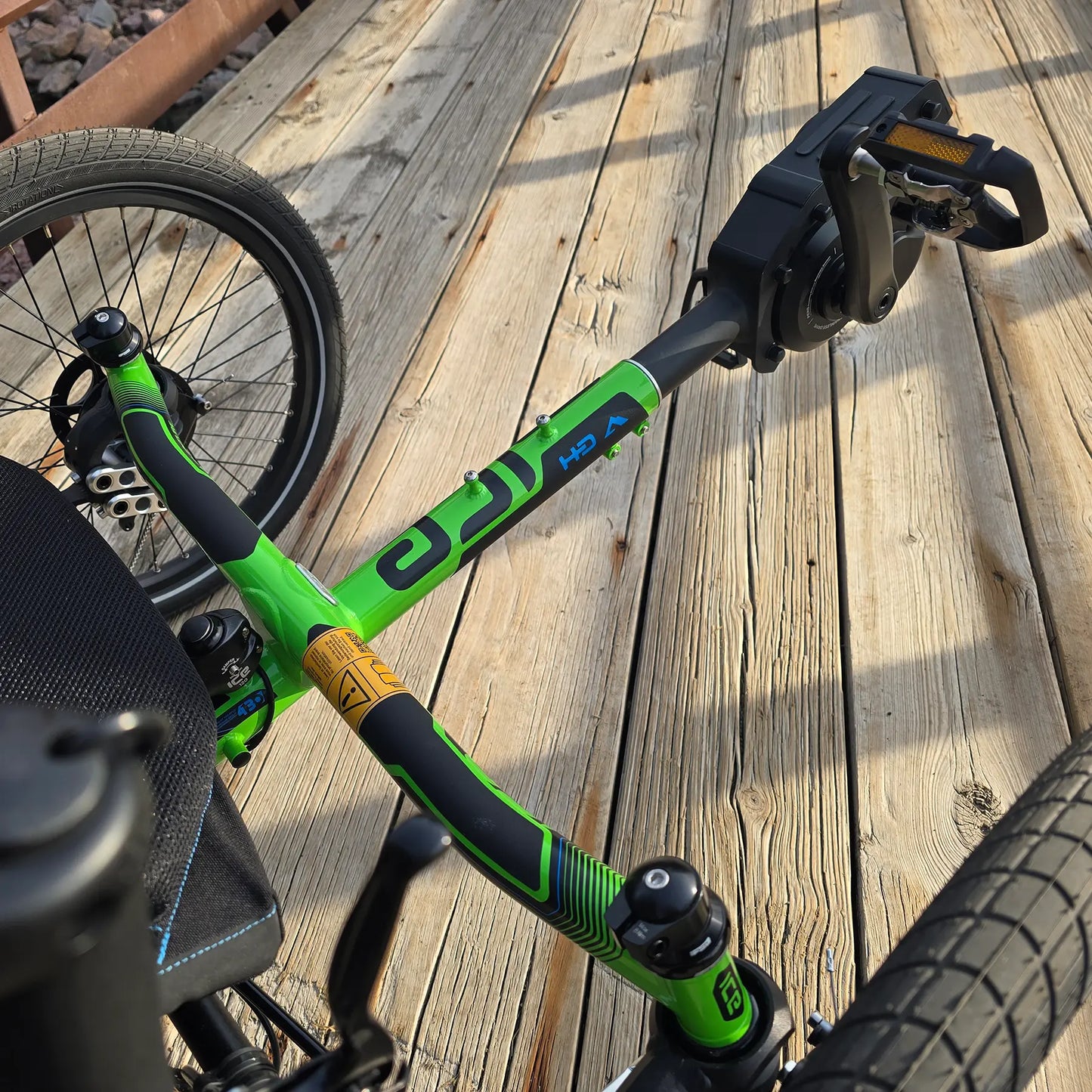 Closeup front view of pedals, motor and frame on the ICE Adventure HD 26 FS PERS Chainless Kiwi Green Recumbent Trike on a bike path.