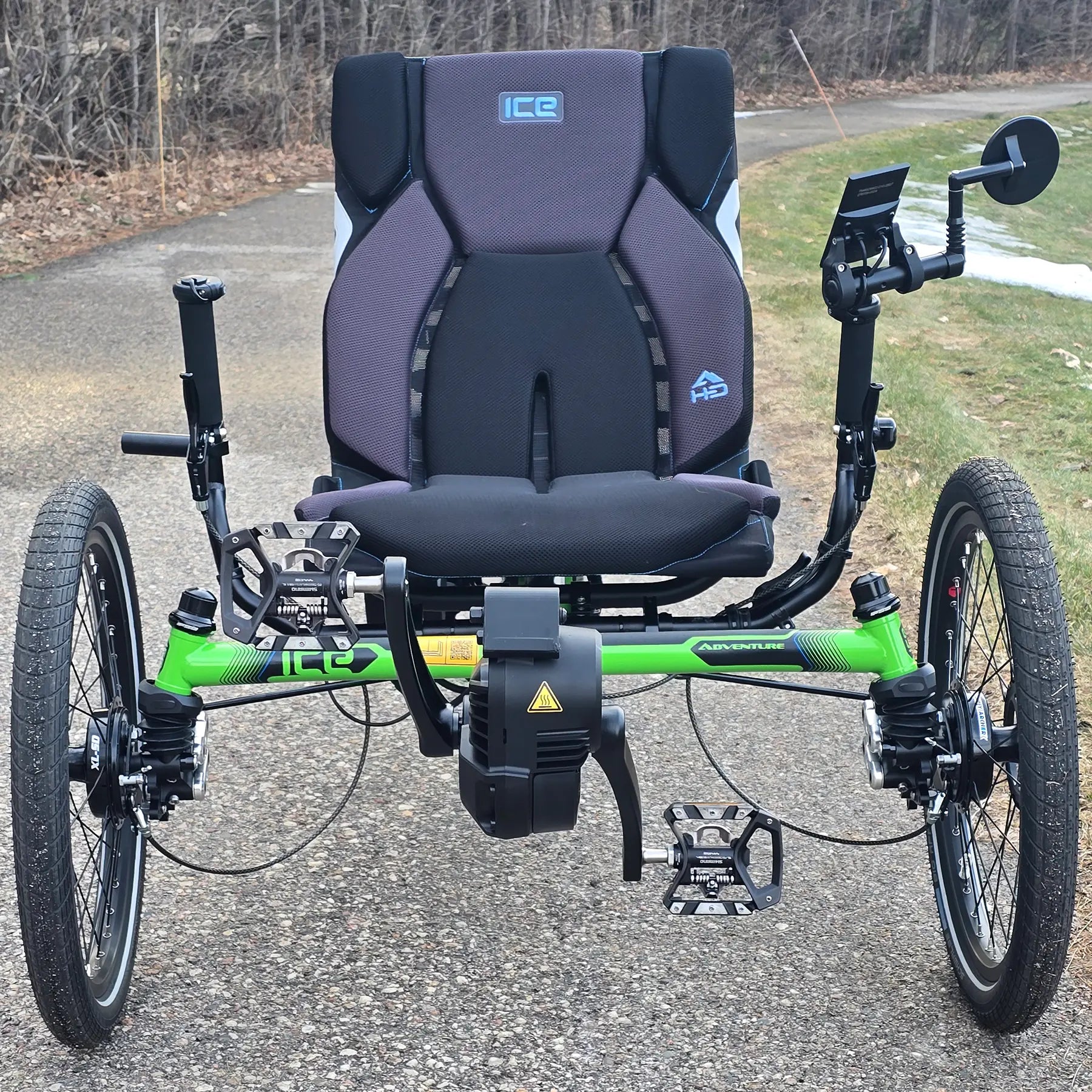 Front view of the ICE Adventure HD 26 FS PERS Chainless Kiwi Green Recumbent Trike on a bike path with trees in the background.