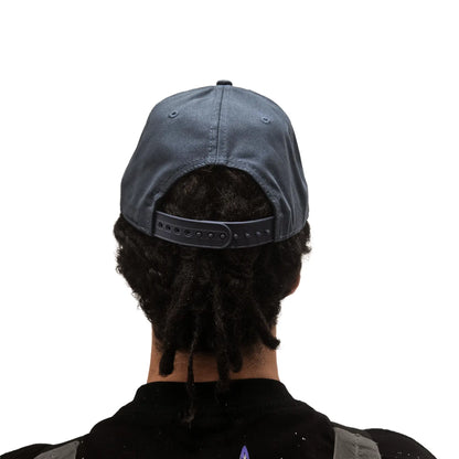 Rear view of the ICE Trucker Cap in Petrol Blue with an adjustable back on a model against a white background. 