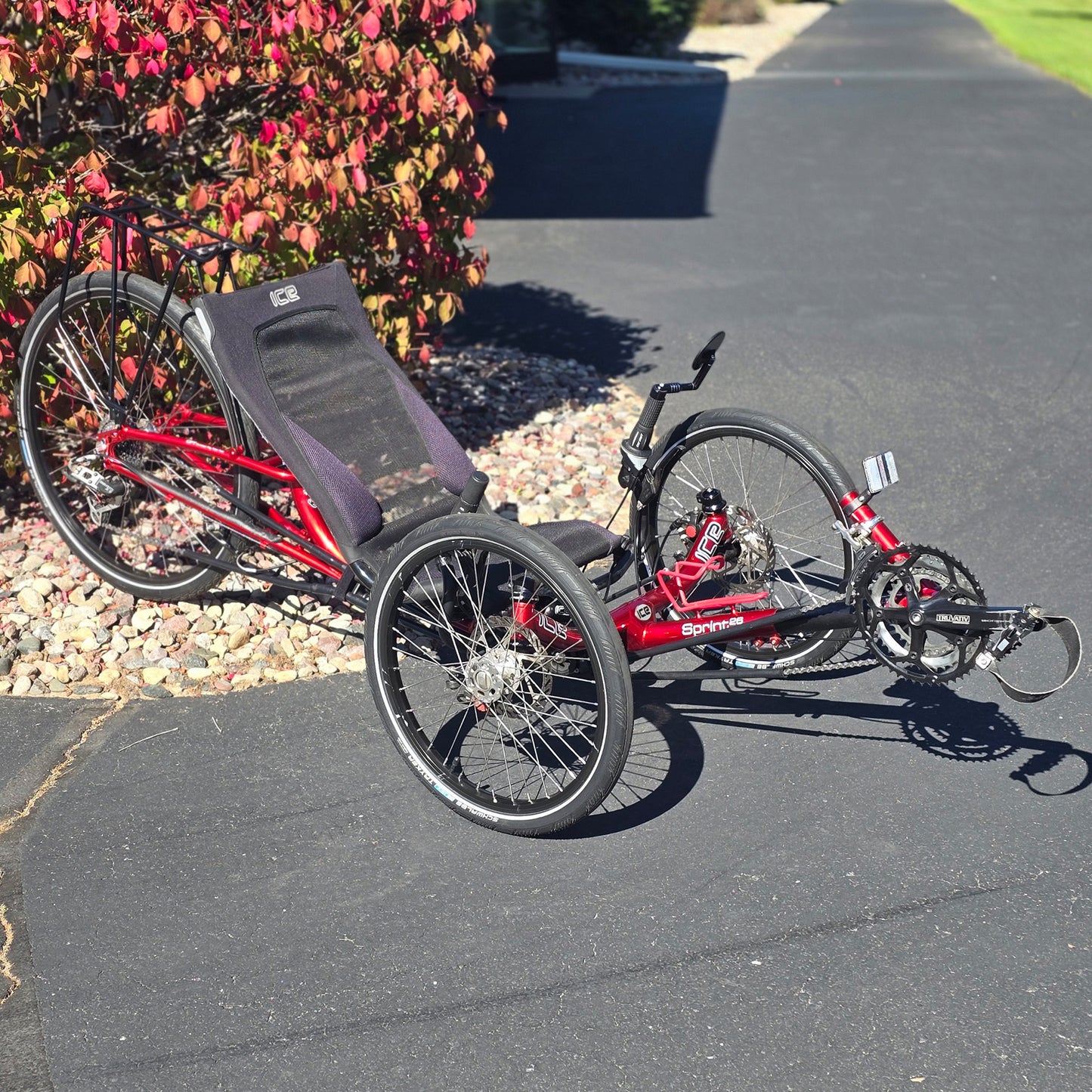 Angled side view of the ICE Used Sprint 26 Red Recumbent Trike in an outdoor setting.