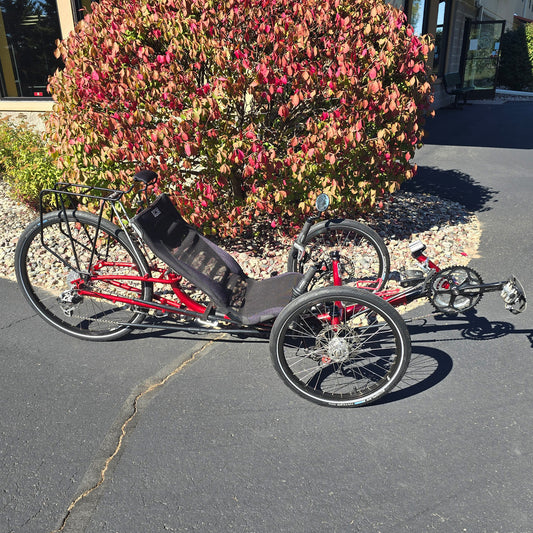 Side view of a used ICE Sprint 26 Recumbent trike in red against a fall background.