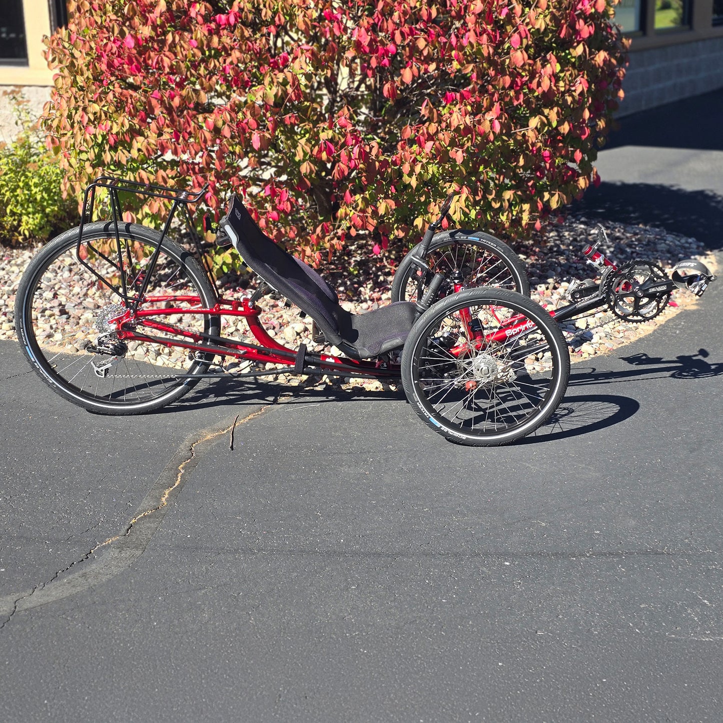 Side view of the ICE Used Sprint 26 Red Recumbent Trike in an outdoor setting.