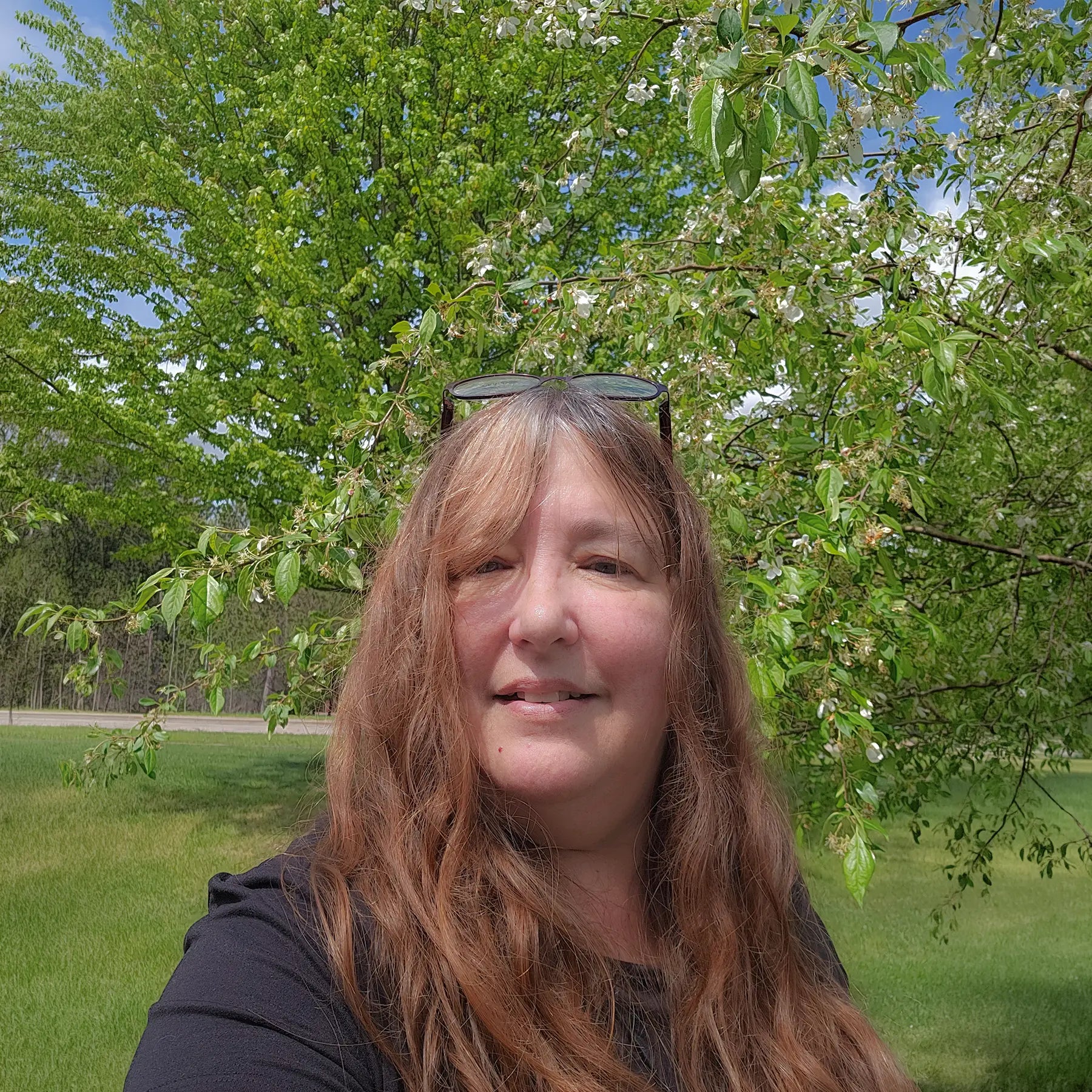 Jessie, Marketing Manger, outside in front of a flowering tree.