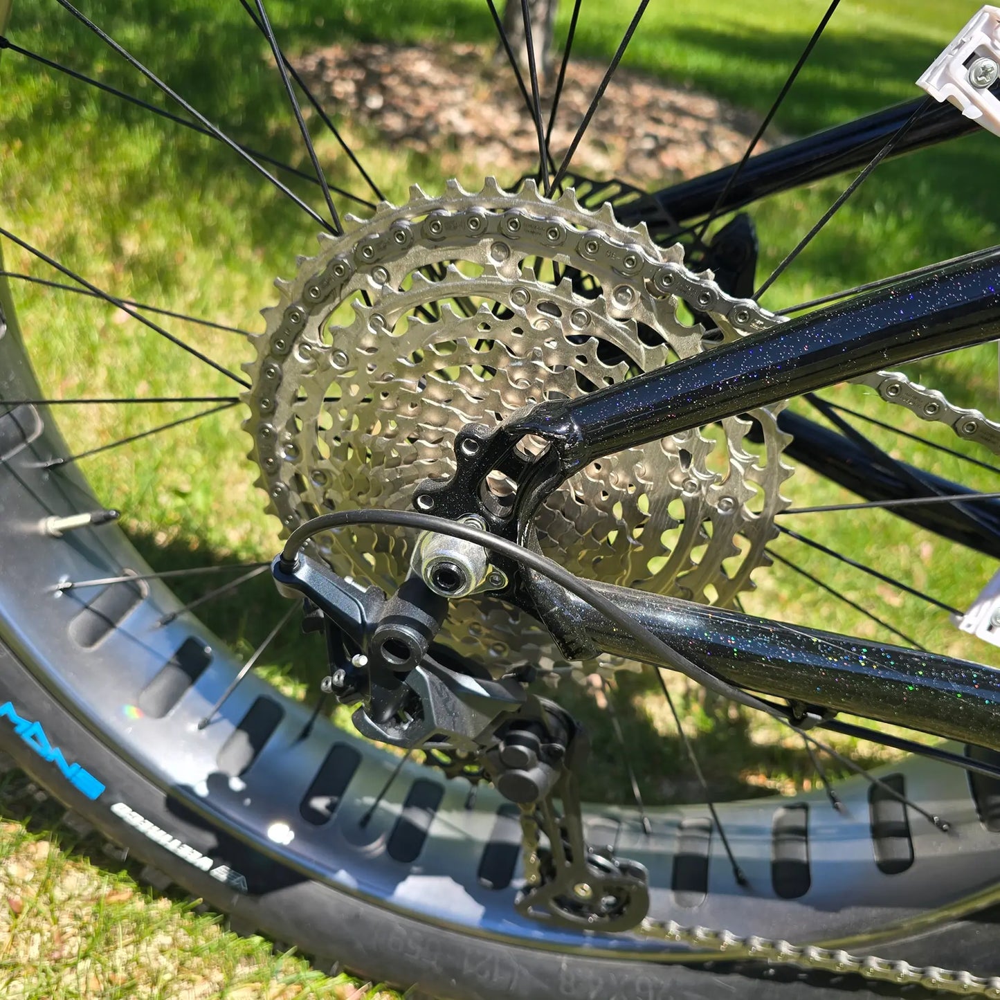 Closeup view of the rear derailleur and cassette on the KHS 4 Season 3000 Fat Bike with Carbon Fork in Black in an outdoor setting.