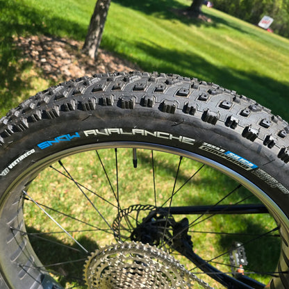 Closeup view of the rear tire on the KHS 4 Season 3000 Fat Bike with Carbon Fork in Black in an outdoor setting.