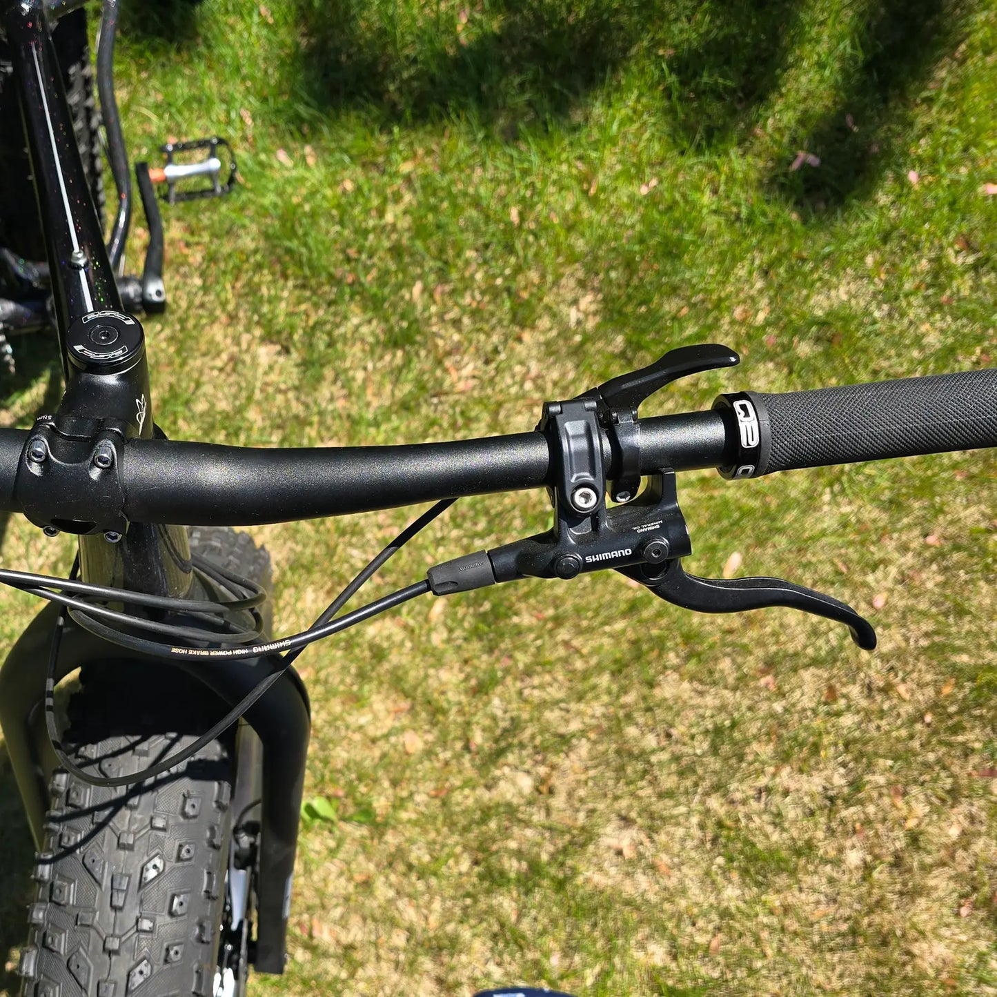 Closeup view of the handlebar on the KHS 4 Season 3000 Fat Bike with Carbon Fork in Black in an outdoor setting.