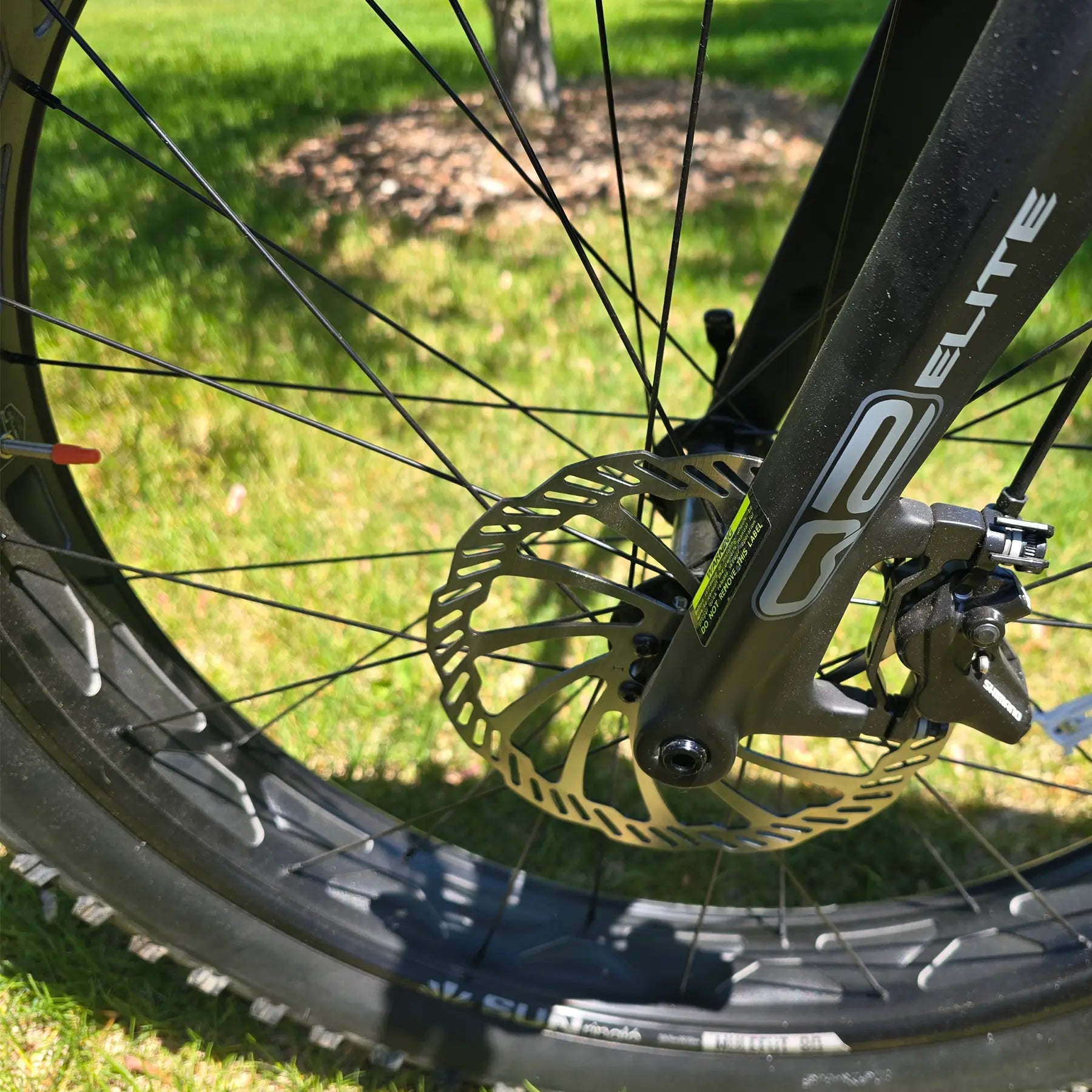 Closeup view of the disc brake and front fork on the KHS 4 Season 5000 Fat Bike with Carbon Fork in Dark Grey in an outdoor setting.