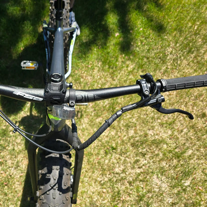Closeup view of the handlebars on the KHS 4 Season 5000 Fat Bike with Carbon Fork in Dark Grey in an outdoor setting.