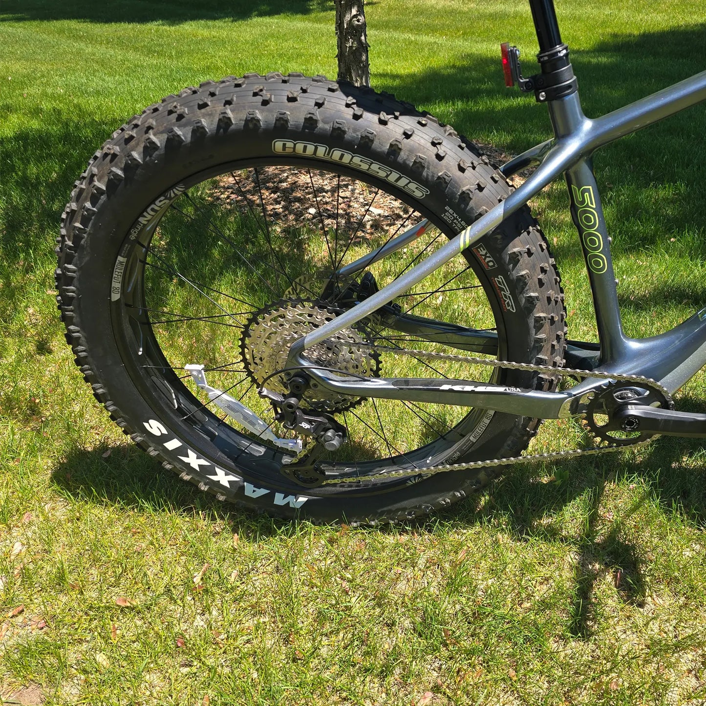Closeup view of the rear wheel and crankset on the KHS 4 Season 5000 Fat Bike with Carbon Fork in Dark Grey in an outdoor setting.