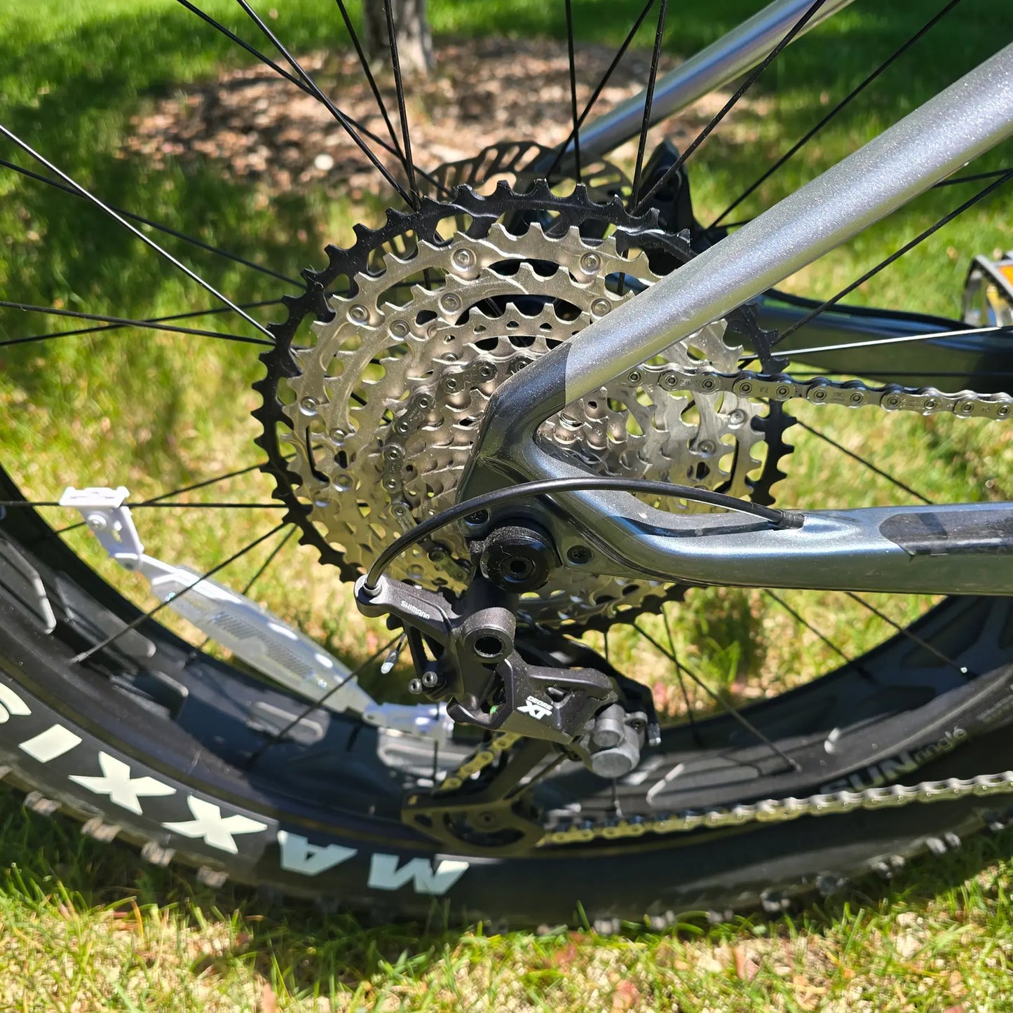 Closeup view of the rear derailleur and cassette on the KHS 4 Season 5000 Fat Bike with Carbon Fork in Dark Grey in an outdoor setting.