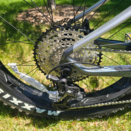 Closeup view of the rear derailleur and cassette on the KHS 4 Season 5000 Fat Bike with Carbon Fork in Dark Grey in an outdoor setting.