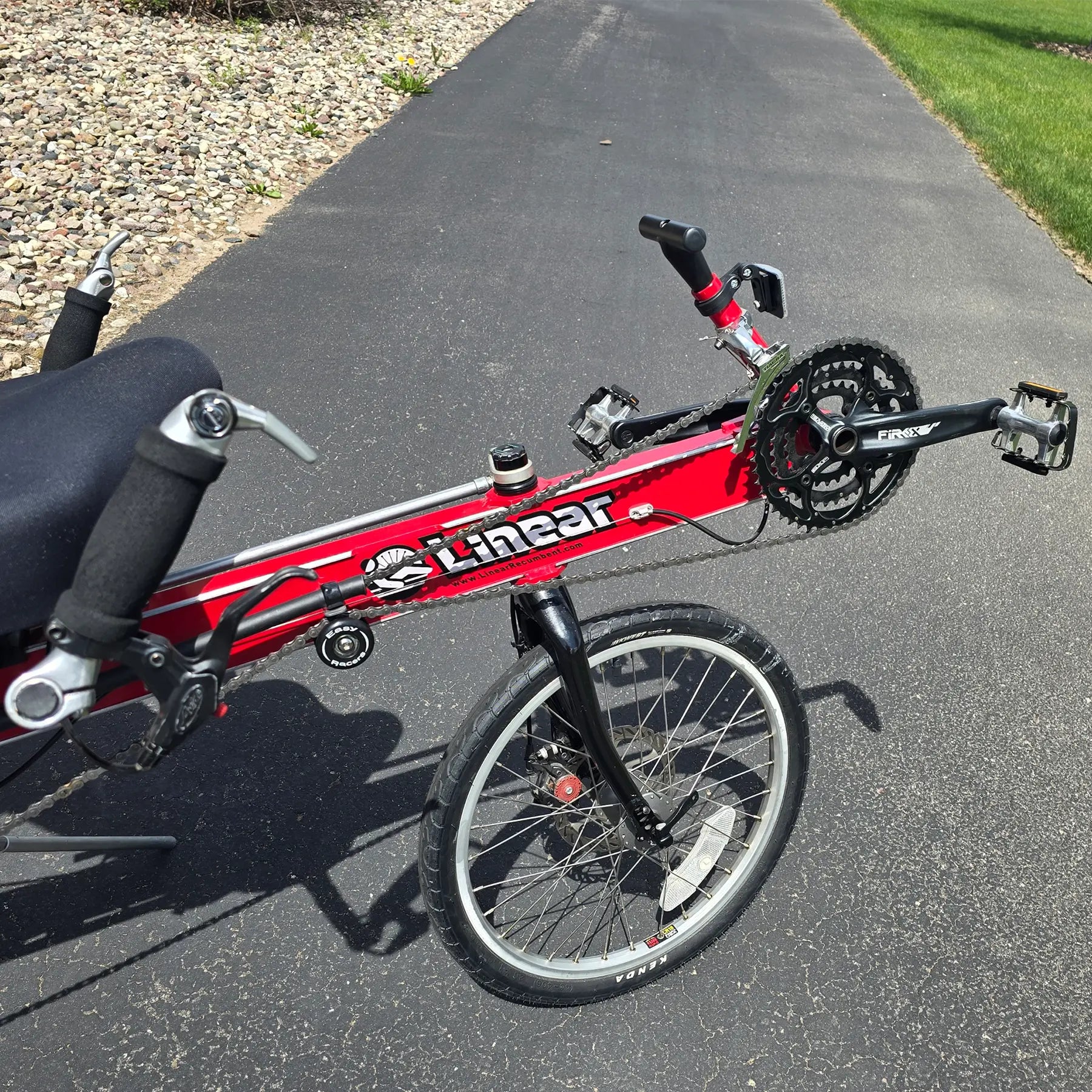 Closeup front view of the Linear Used Red Recumbent Bike in an outdoor setting.