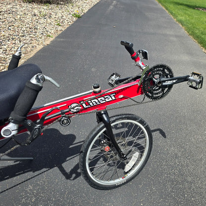 Closeup front view of the Linear Used Red Recumbent Bike in an outdoor setting.