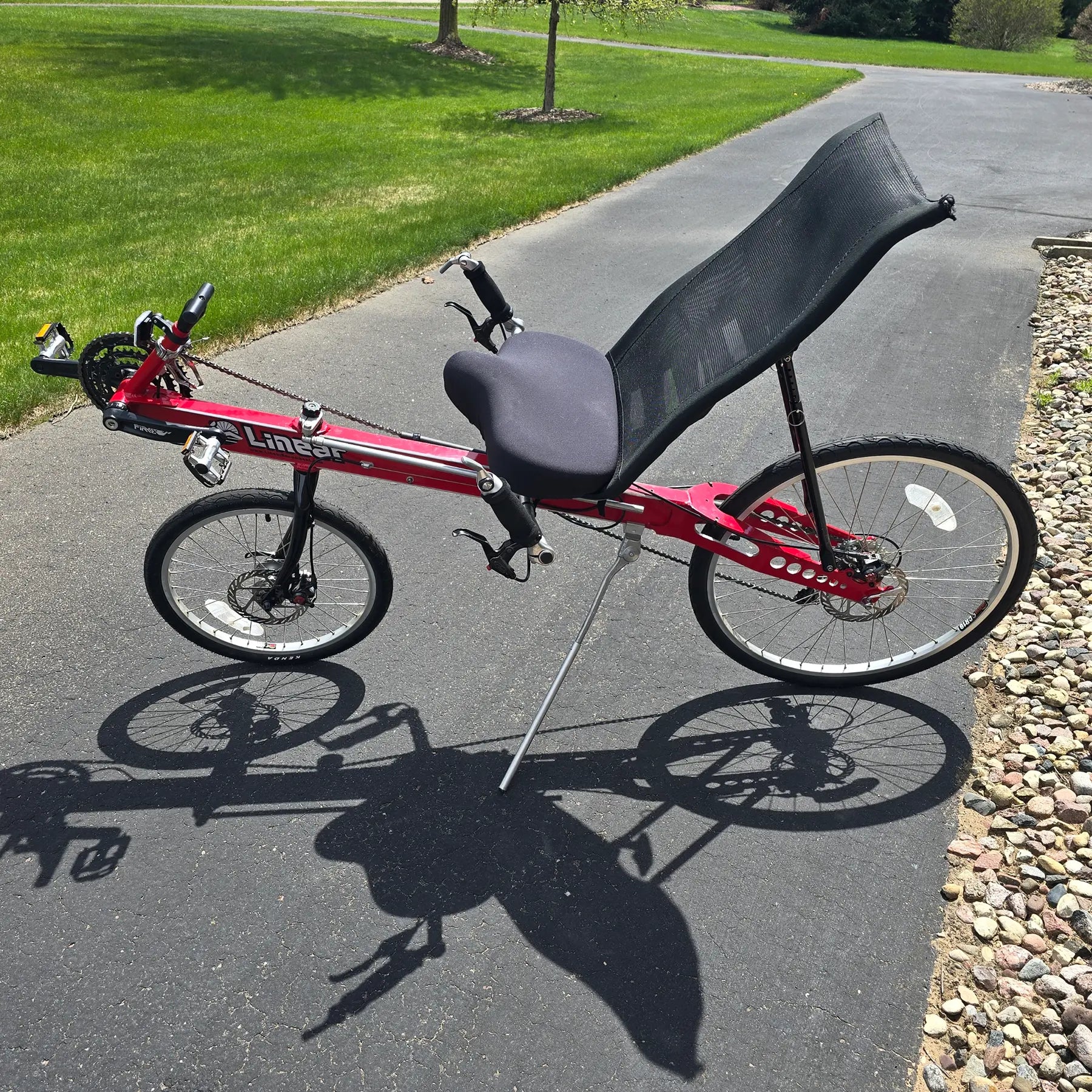 Non-drive side view of the Linear Used Red Recumbent Bike in an outdoor setting.