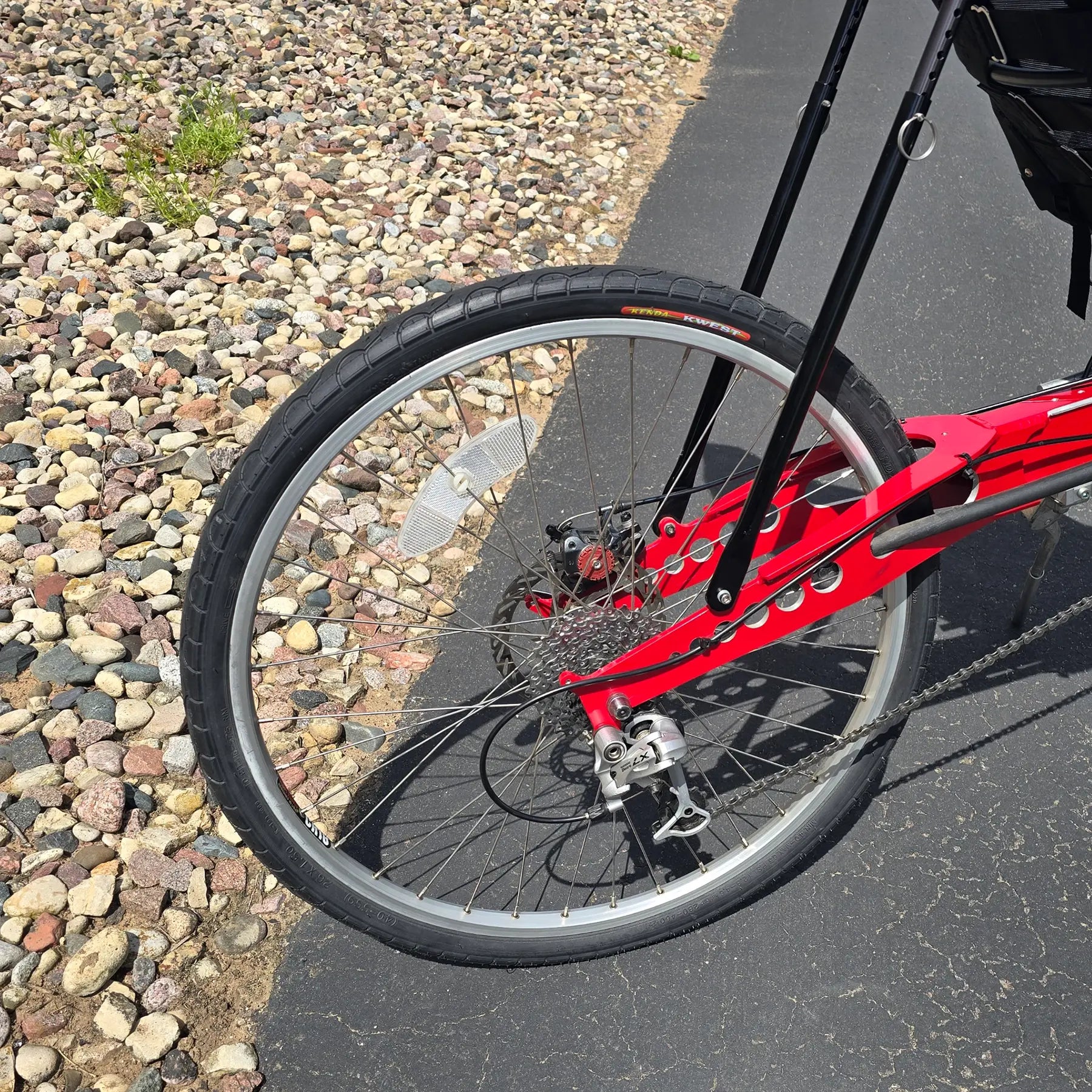 Closeup rear view of the Linear Used Red Recumbent Bike in an outdoor setting.