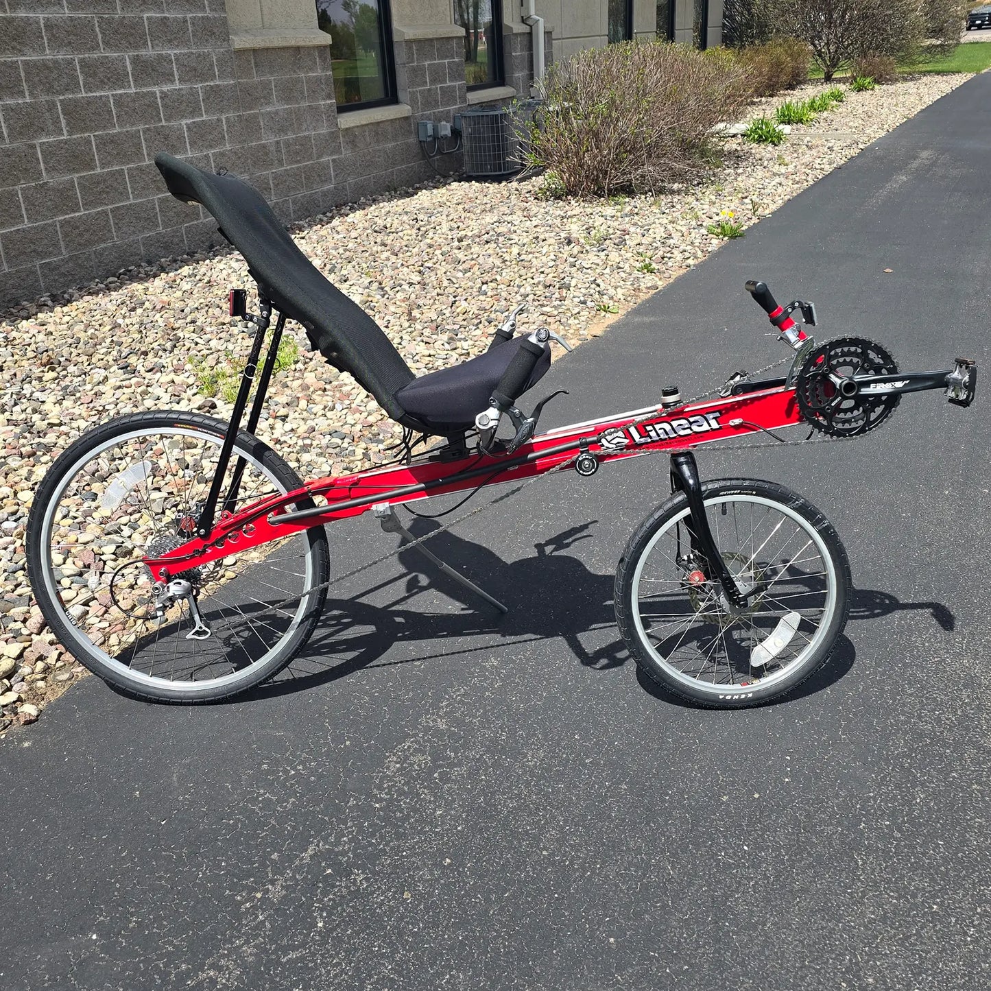 Side view of the Linear Used Red Recumbent Bike in an outdoor setting.