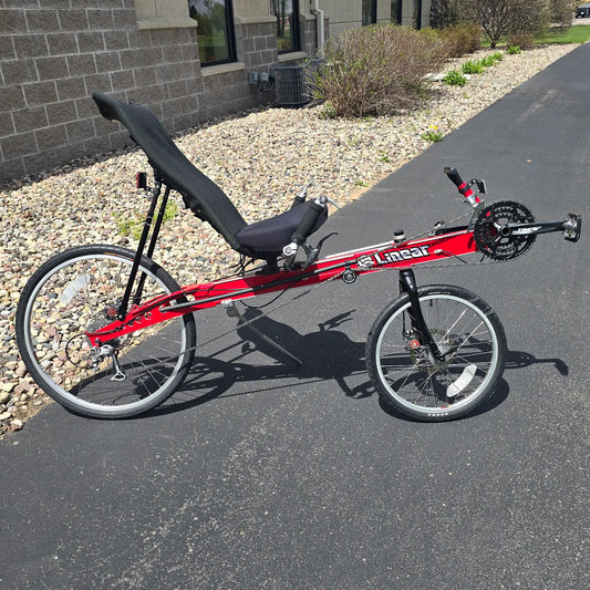 Side view of the Linear Used Red Recumbent Bike in an outdoor setting.