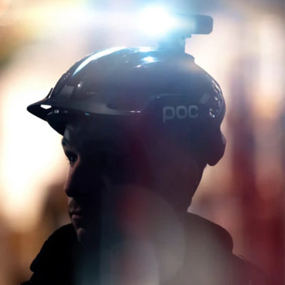 Image of the Moon Rigel Max 1500 Lumen Headlight in black mounted on a helmet against a blurry reddish background.