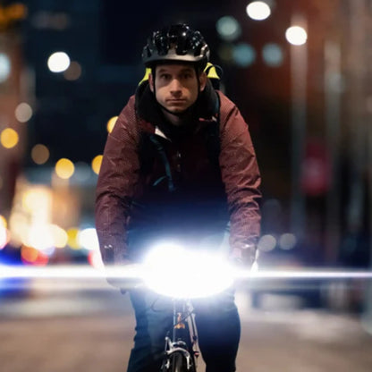 Image of the Moon Rigel Pro 1000 Lumen Headlight lighted up on a bike while a man rides through a city.