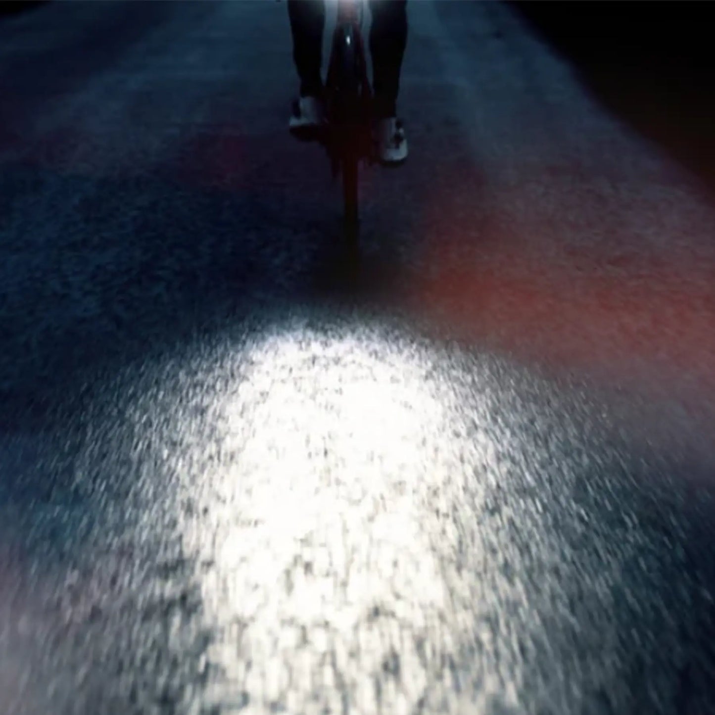 Image of the reflection on the street from the Moon Rigel Pro 1000 Lumen Headlight while a man rides through a city.