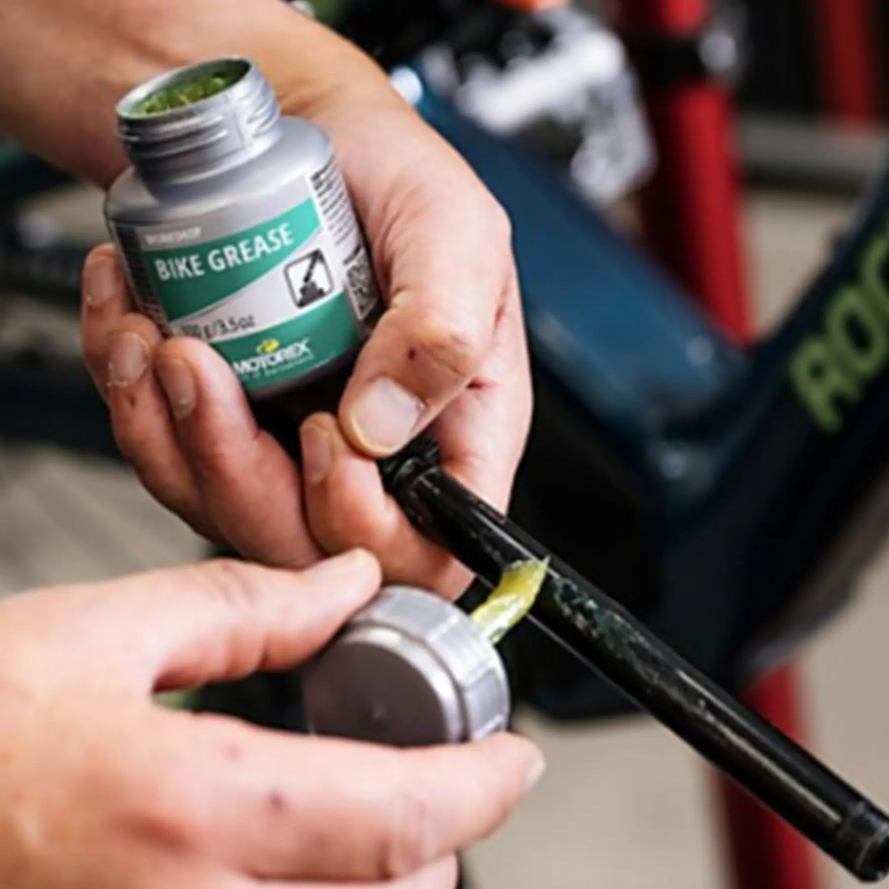 Image of mechanic using a jar of Motorex Bike Grease 100 grams in silver and green on a bike part.