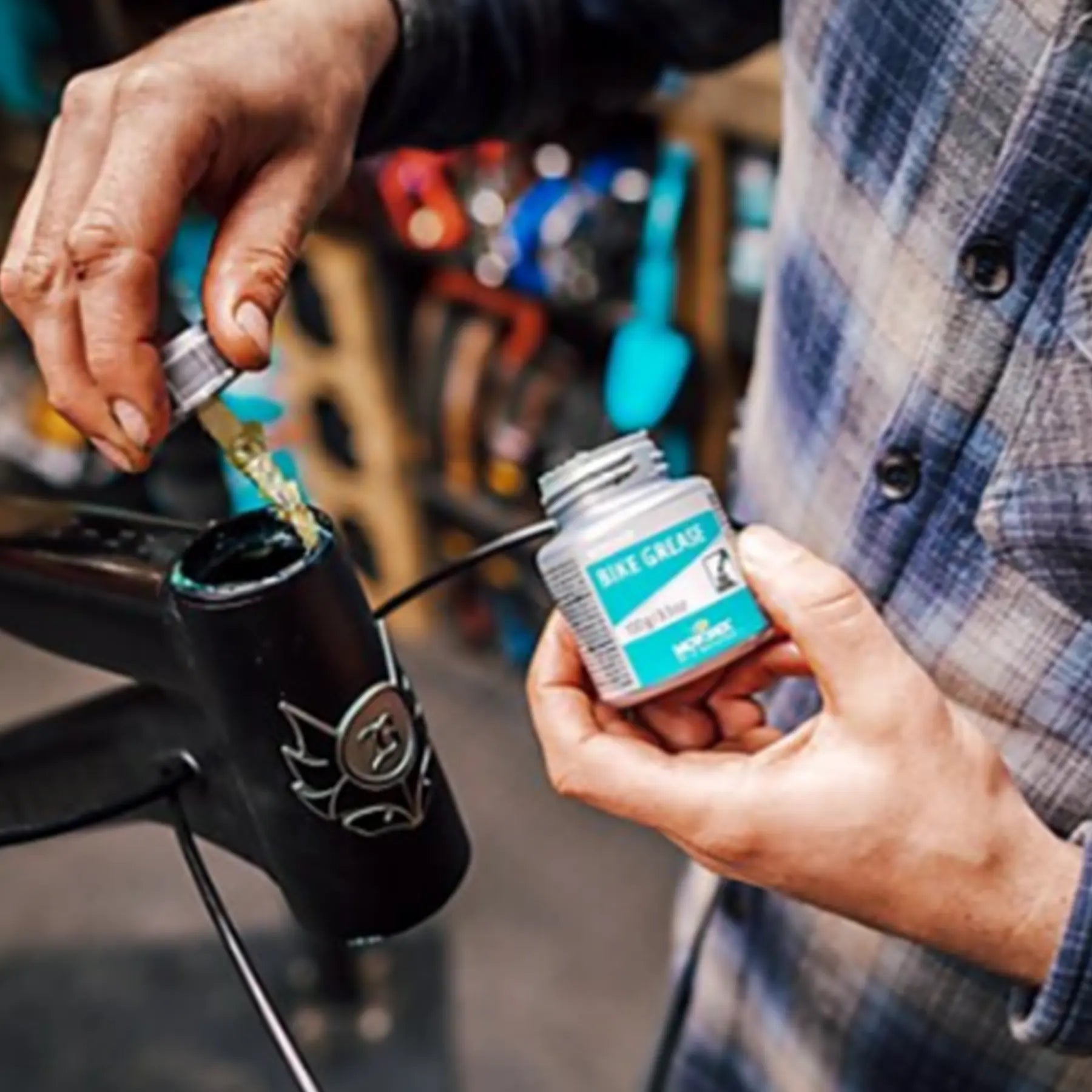 Image of mechanic using a jar of Motorex Bike Grease 100 grams in silver and green on a headset.